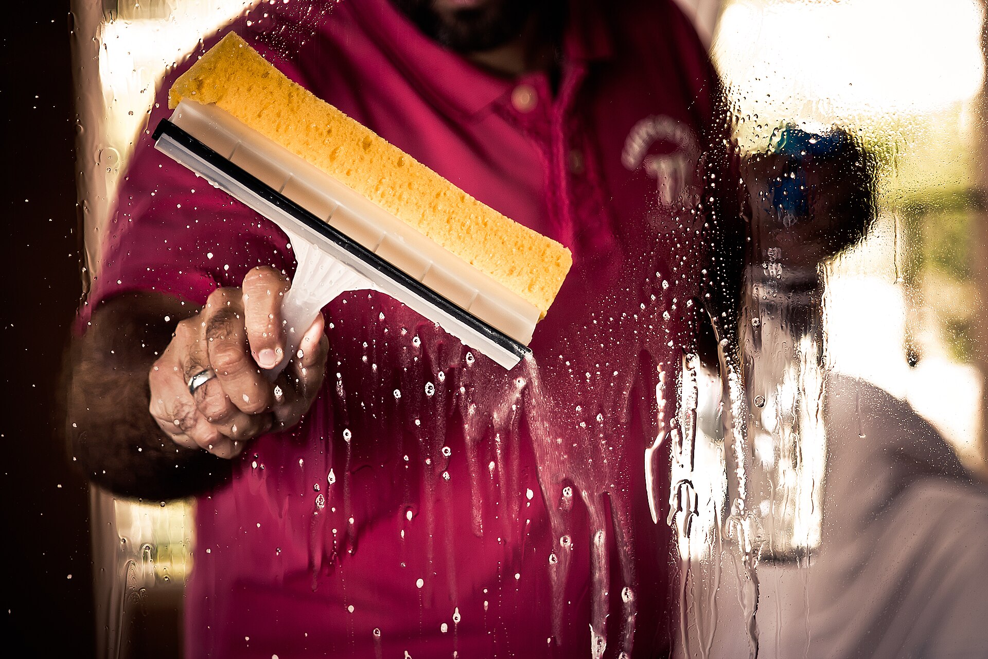 A squeegee wiping a soapy window clean